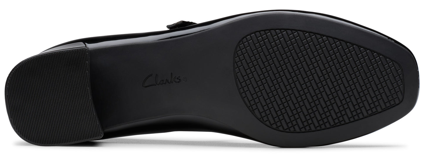 The black textured rubber outsole of a shoe with a low block heel and the word Clarks embossed in the center of the arch.