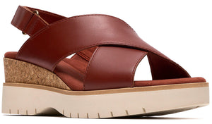 A red-brown sandal with crisscrossing straps, a cork wedge heel, and a white platform sole.
