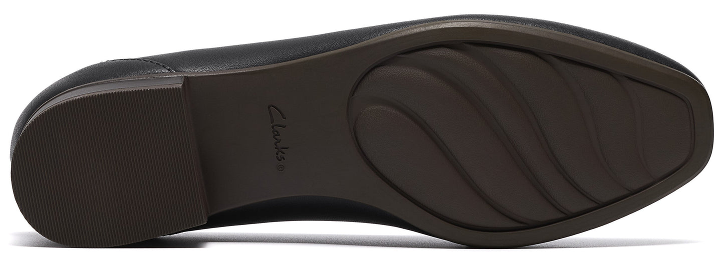 The underside of a black shoe with a low block heel and a curved tread pattern on the sole, featuring the word Clarks embossed in the center.