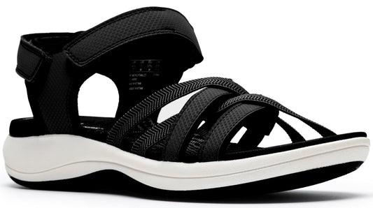 A women's sandal with an adjustable velcro heel strap and multiple crossing black straps over the toes on a white sole.