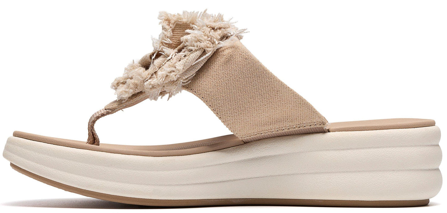 A tan flip-flop with a thick white sole and a decorative tan flower on the strap.