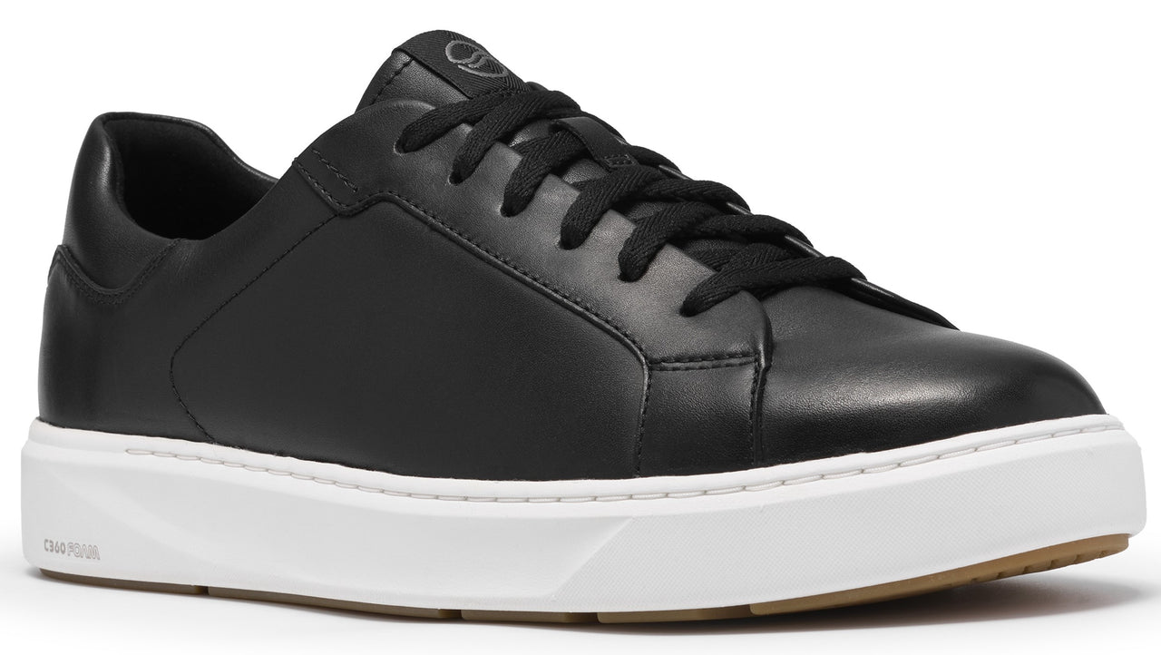 A minimalist black leather low-top sneaker with black laces, a clean white rubber midsole, and a gum-colored outsole.