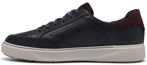 A low-top, black leather sneaker with a dark navy suede toe overlay, a thick cream-colored rubber sole, dark grey laces, and a contrasting maroon suede heel tab.