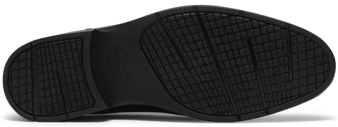 The bottom sole of a black shoe features a patterned grid tread design with subtle diagonal grooves for traction and a faintly embossed logo in the center arch.