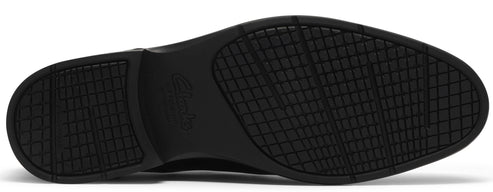 A close-up view of the bottom sole of a black dress shoe, showing a patterned tread design with a grid texture and the word Clarks embossed in the center of the heel area.