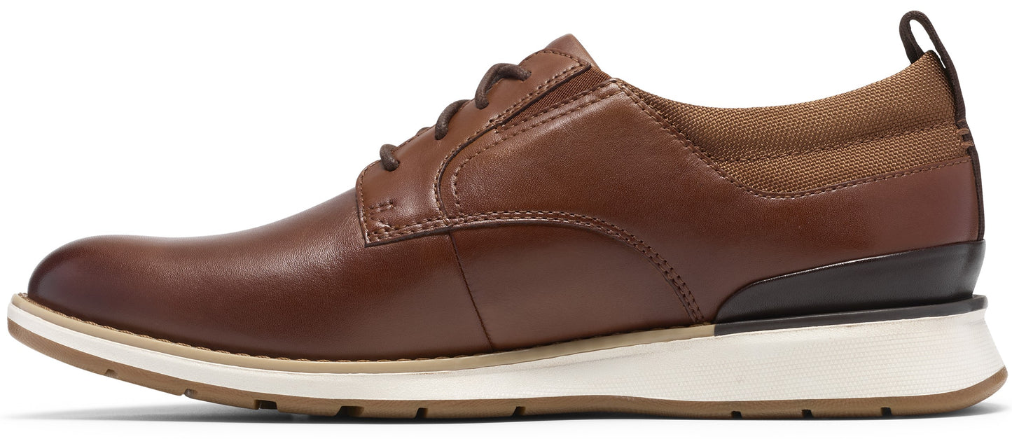 A brown leather men's dress sneaker with dark brown leather heel detailing, tan fabric collar, dark laces, and a white, textured rubber sole.