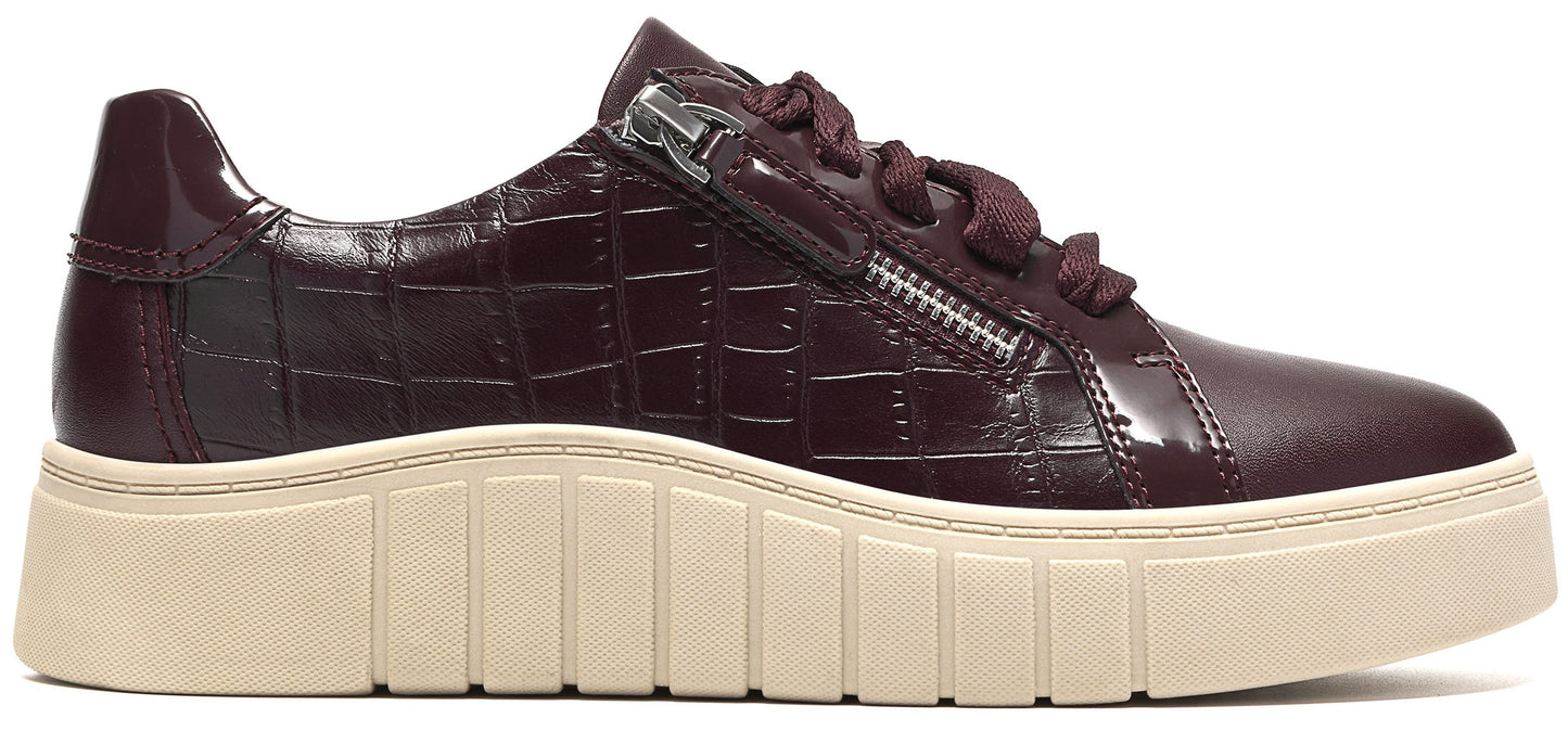 A maroon, crocodile-textured sneaker with a thick, ribbed, beige platform sole and a silver side zipper detail.