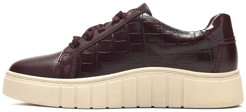 A low-top sneaker in dark burgundy patent leather with a textured, croc-embossed finish and a thick, cream-colored rubber platform sole.