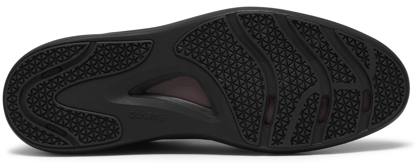 The black textured rubber outsole of a shoe, featuring a geometric triangle pattern for grip and a recessed central arch section.
