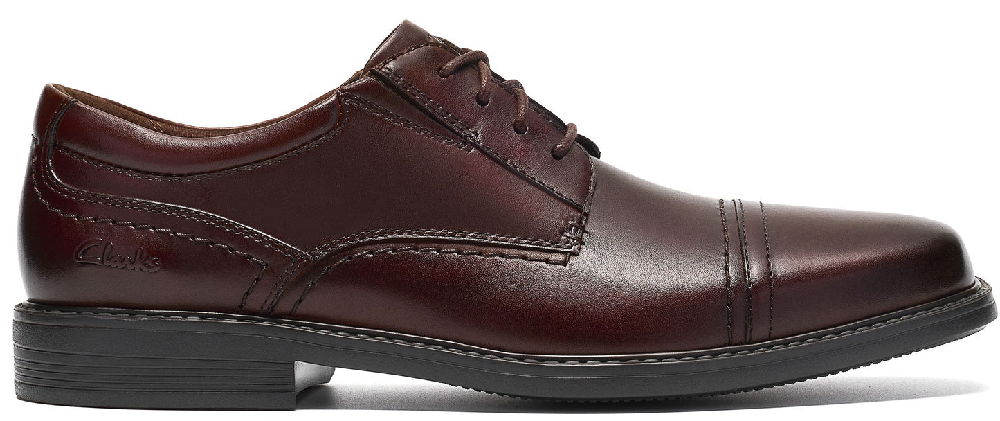 A dark brown leather cap-toe oxford dress shoe with laces and a low black sole, featuring stitched detailing and a Clarks logo embossed on the side.