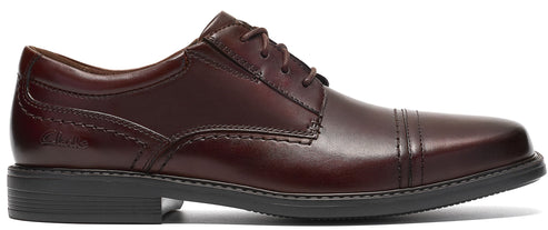 A dark brown leather cap-toe oxford dress shoe with laces and a low black sole, featuring stitched detailing and a Clarks logo embossed on the side.