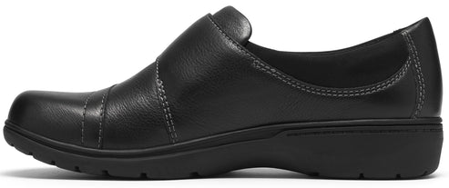 A black leather slip-on shoe with a rounded toe, topstitching details, and a dark, low-profile rubber sole.