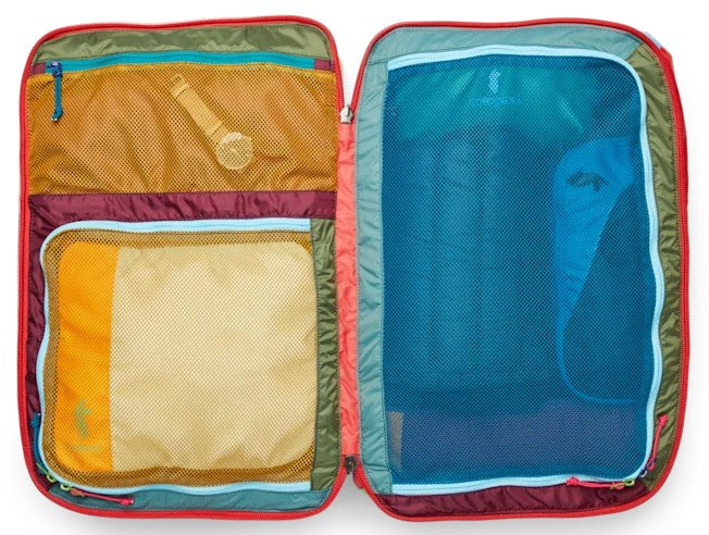 An open suitcase featuring multicolored sections and mesh compartments for organized packing, with a watch visible inside the upper left mesh pocket.