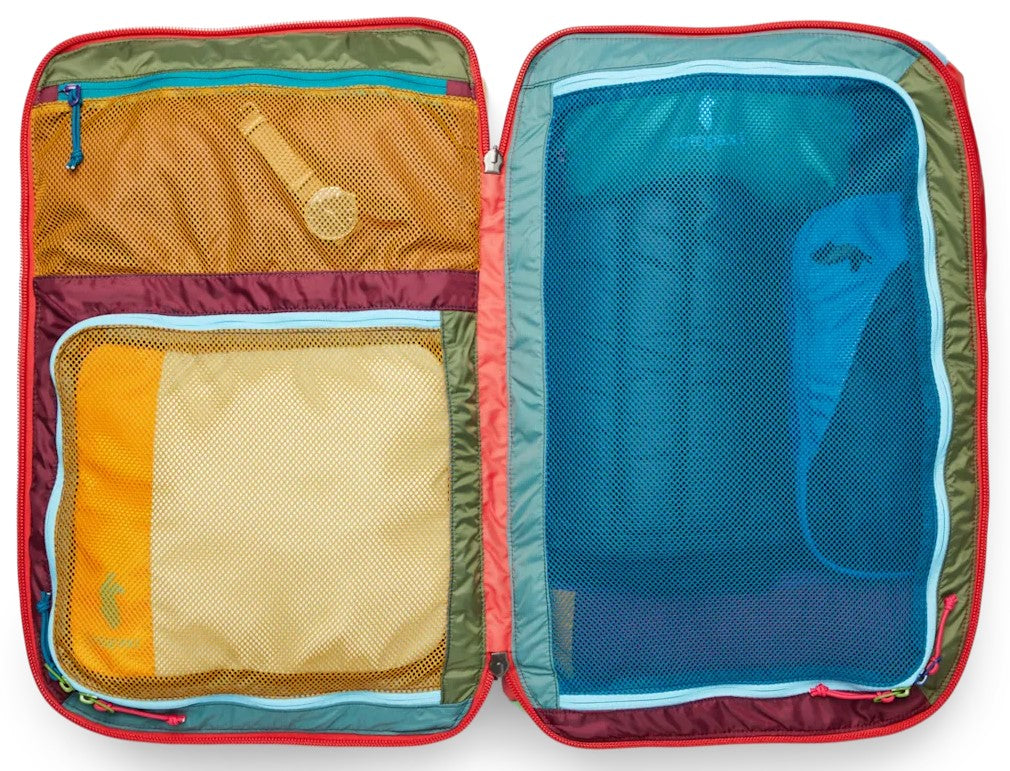 An open, multi-colored travel suitcase featuring various interior compartments with mesh zippered pockets, showcasing internal organization with packing cubes and packed items.