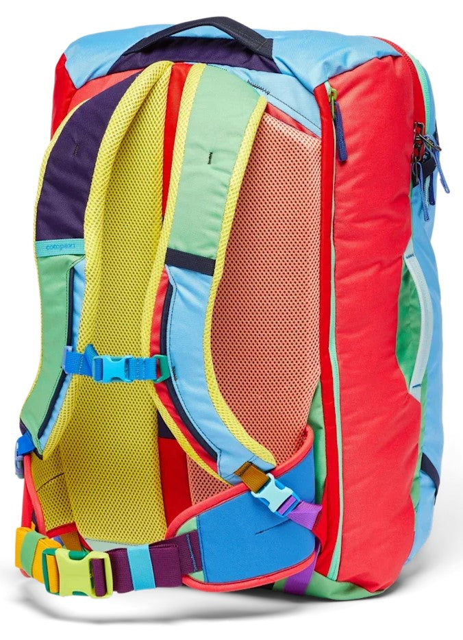A brightly colored travel backpack shown from the rear view, featuring yellow mesh padding on the shoulder straps and back panel, with adjustable blue and yellow buckles at the chest and waist, and multi-colored fabric panels including red, light blue, and green.