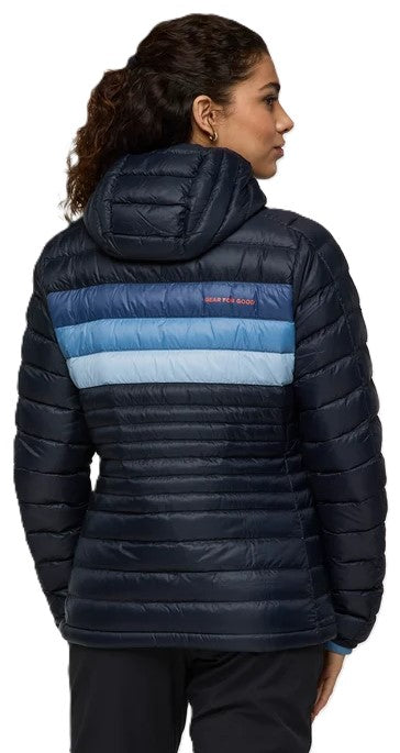 A woman seen from behind wearing a dark navy blue hooded quilted down jacket with horizontal blue and light blue stripes across the upper back and shoulders.