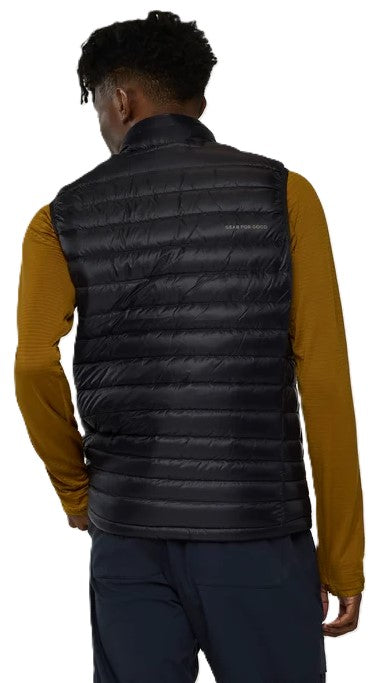 A back view of a person wearing a black quilted down vest over a long-sleeved mustard yellow shirt and dark navy trousers.