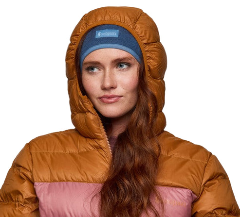 A woman wearing a puffy jacket with a hood and blue headwear with a rectangular logo.