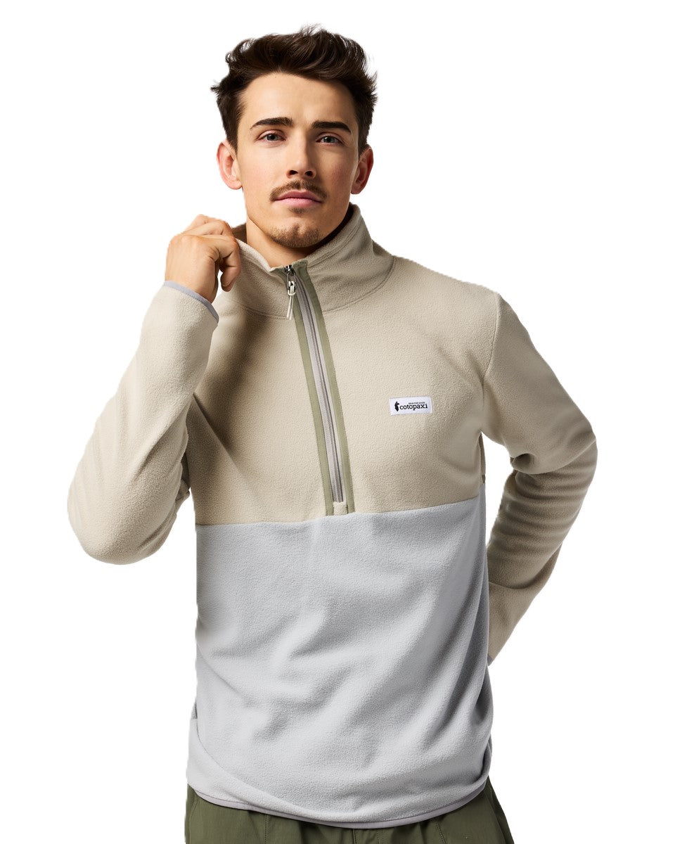 Man wearing a beige and gray color-blocked fleece pullover with a quarter-zip closure and a small logo patch.