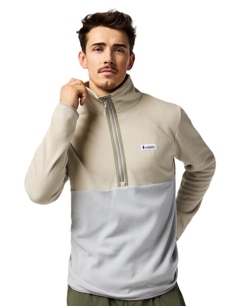 Man wearing a beige and gray color-blocked fleece pullover with a quarter-zip closure and a small logo patch.