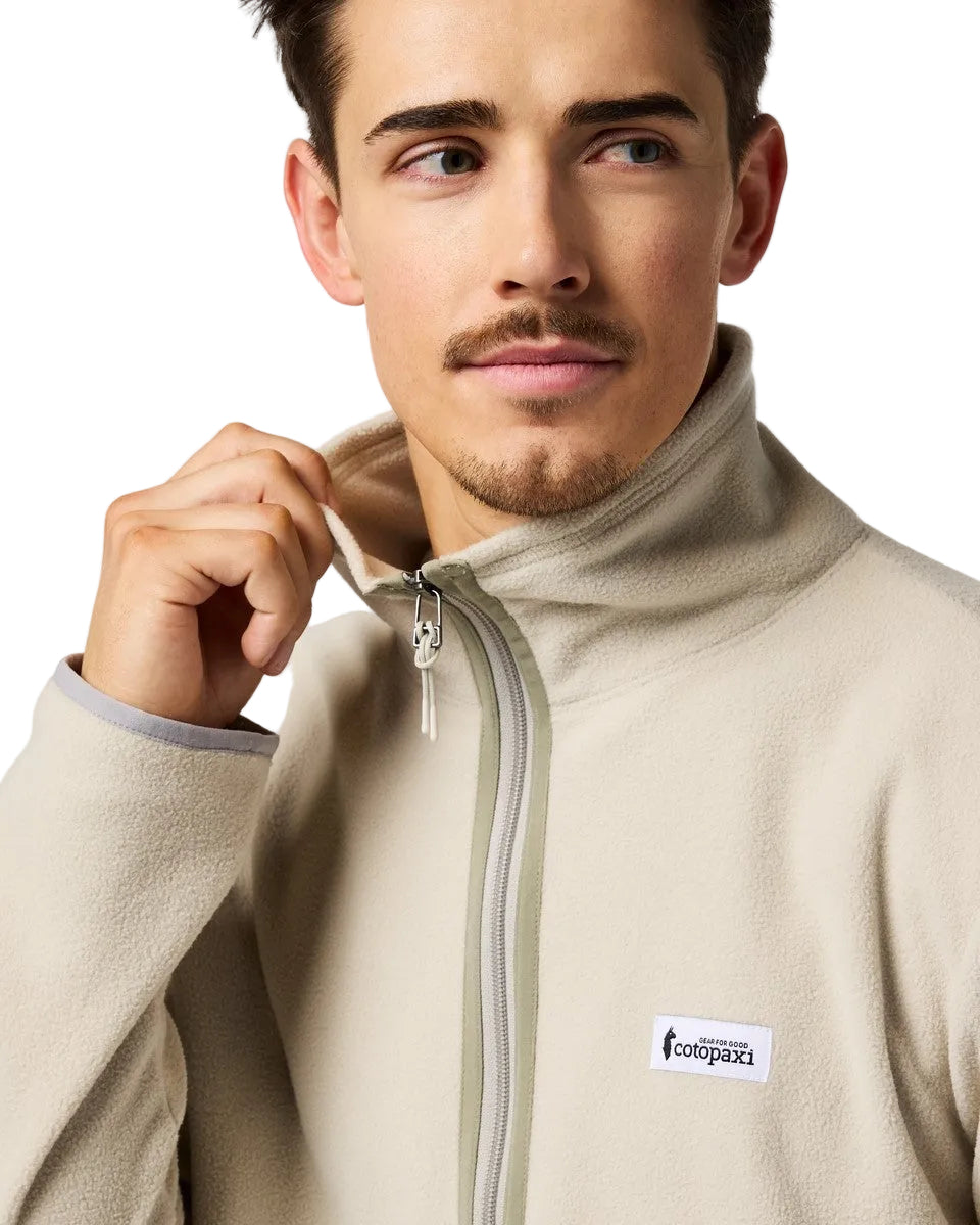 Man wearing beige fleece jacket with grey zipper; a logo says "cotopaxi"