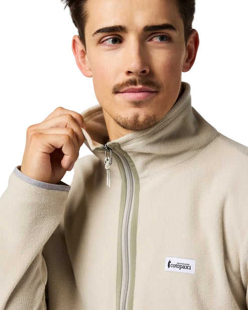 Man wearing beige fleece jacket with grey zipper; a logo says "cotopaxi"