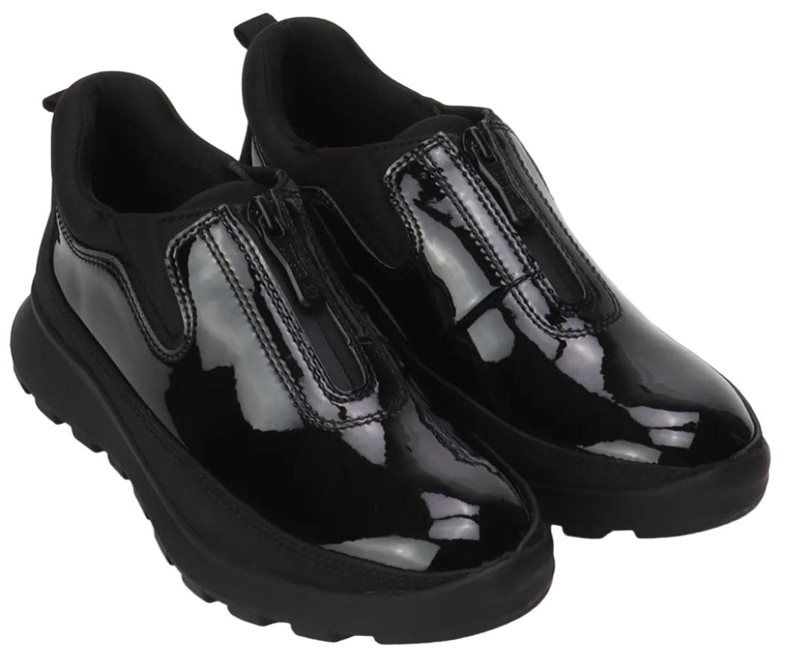 A pair of black, glossy, patent leather slip-on shoes with a central vertical zipper and chunky, black lug soles, isolated on a white background.
