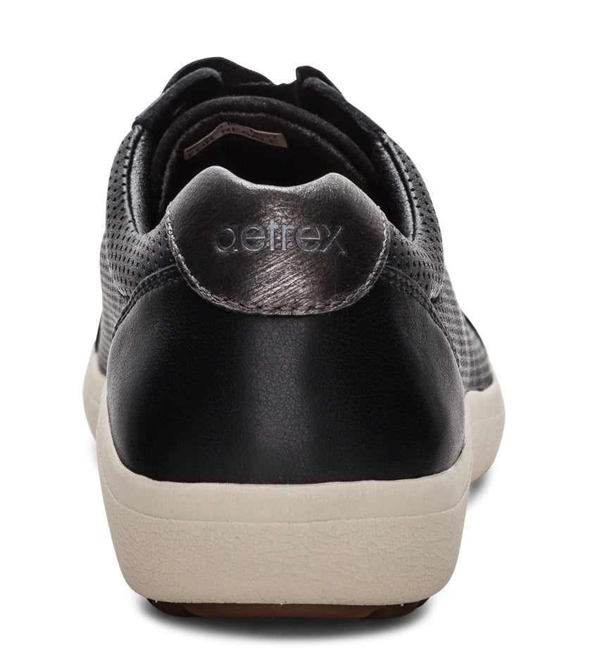 Rear view of black perforated leather-like sneakers with tan soles and brand labeled on silver accent patch.