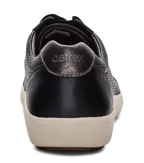Rear view of black perforated leather-like sneakers with tan soles and brand labeled on silver accent patch.