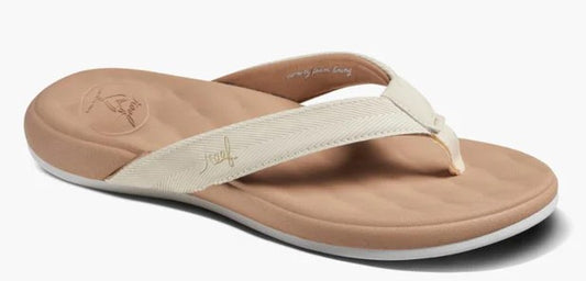A tan flip-flop with a cream-colored strap featuring the word reef embroidered on the side, viewed from a side angle.