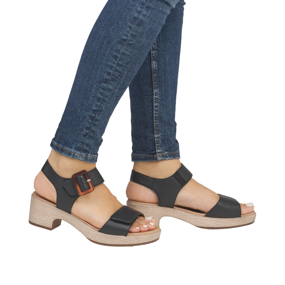 A person wearing open-toed heeled sandals with a buckled strap.