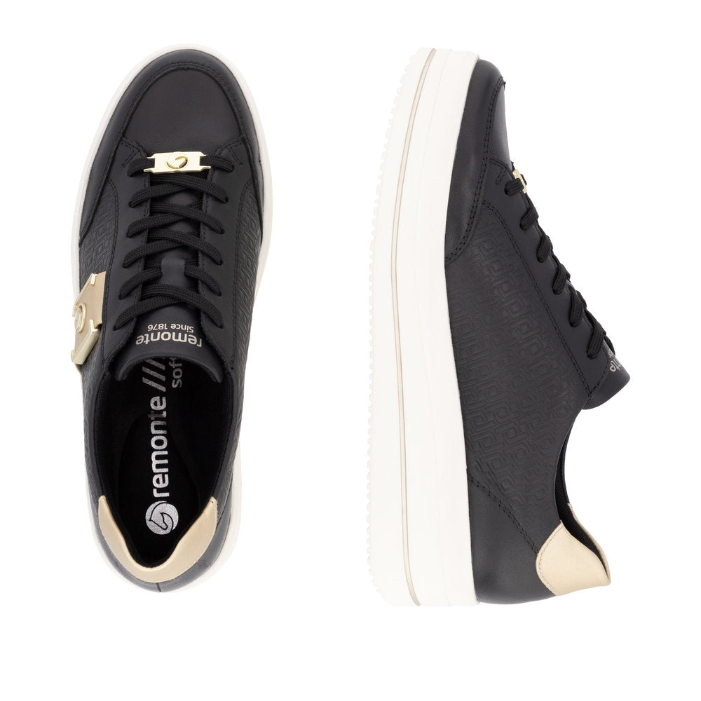 Pair of black sneakers with gold accents, white soles, and black laces.