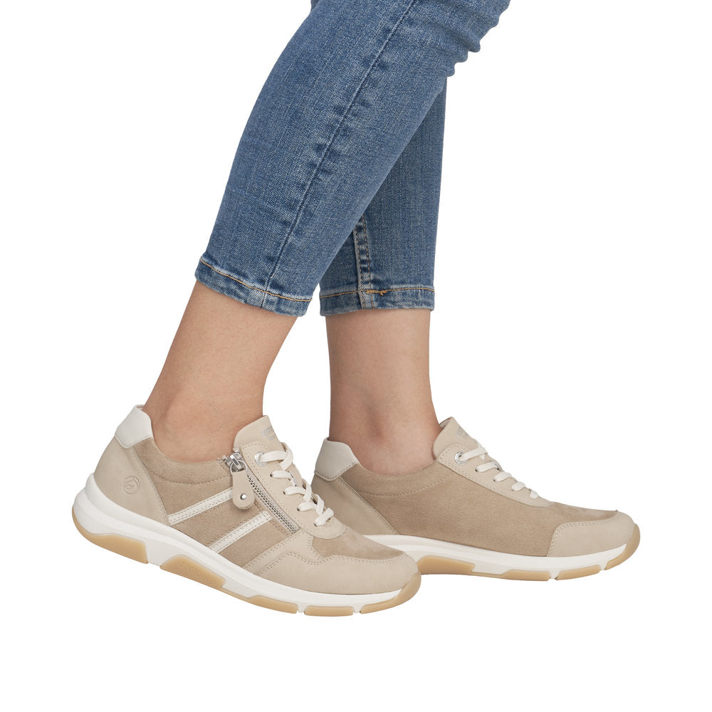 Beige sneaker with white soles, laces, and stripe detail, shown on feet.