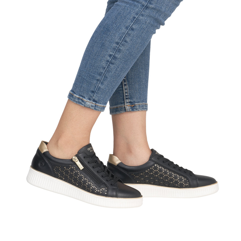 A pair of black perforated leather sneakers with zipper and white soles.