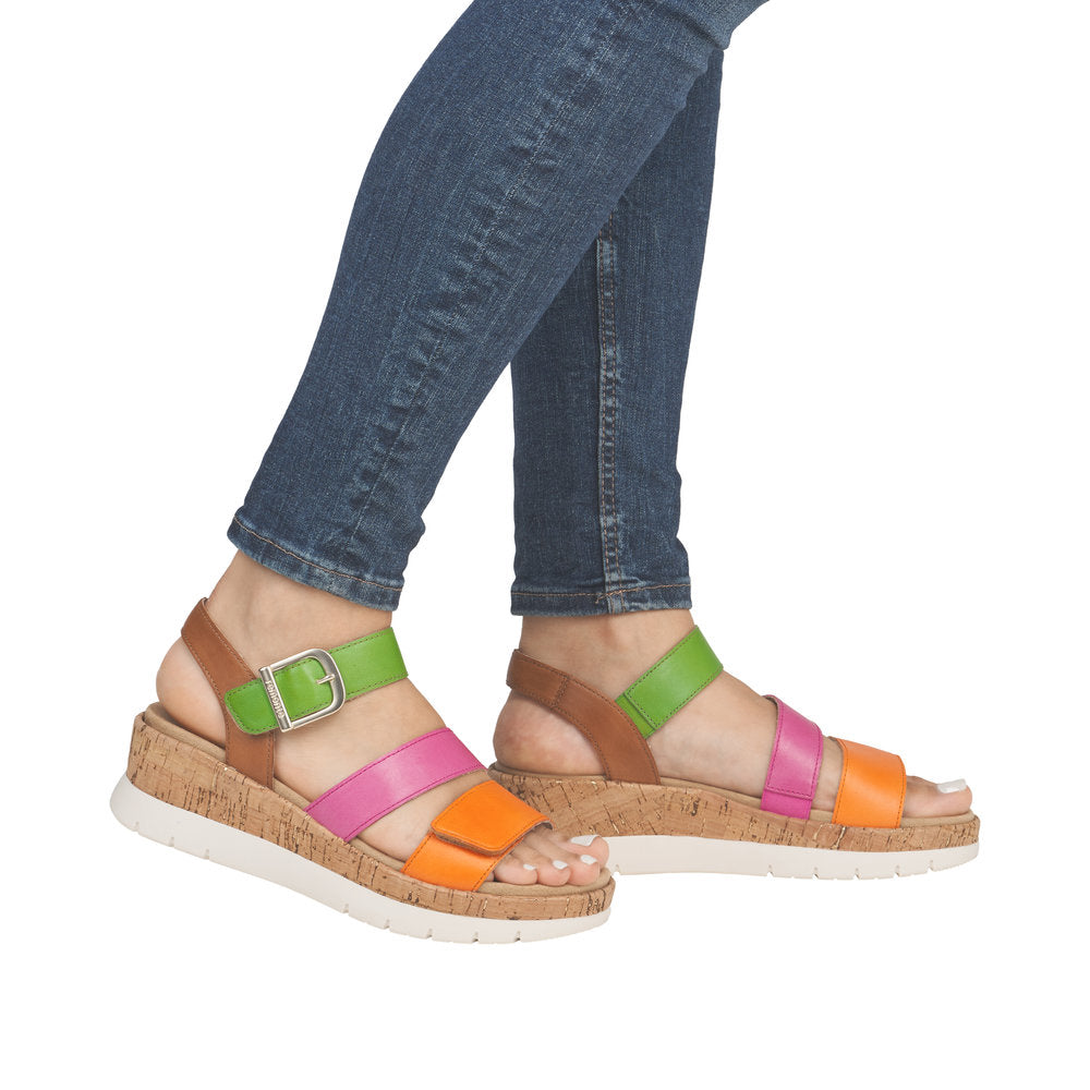 A woman wearing colorful platform sandals with buckled straps in orange, pink, and green.