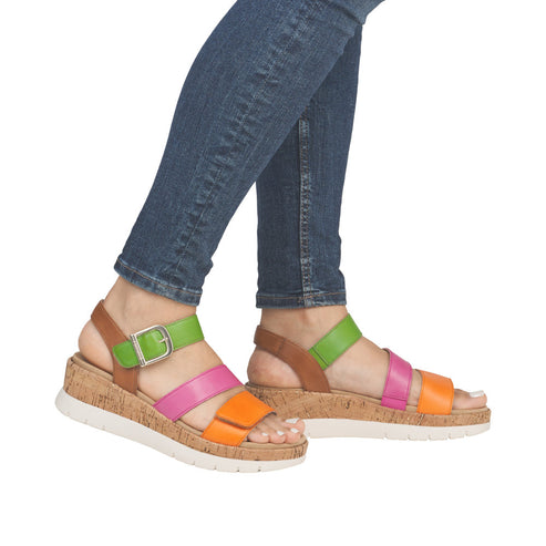A woman wearing colorful platform sandals with buckled straps in orange, pink, and green.