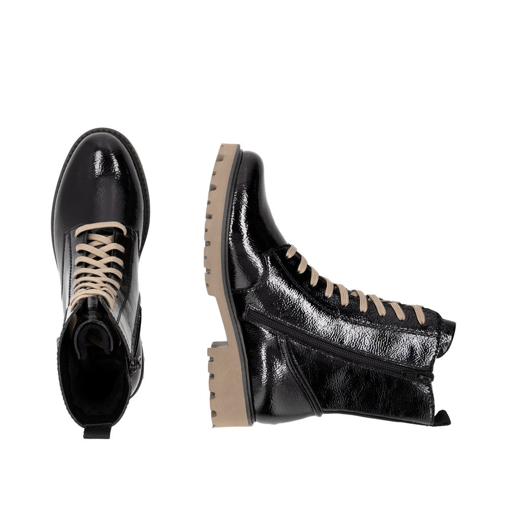 Two black patent leather combat boots with beige laces and soles, one upright and one on its side.