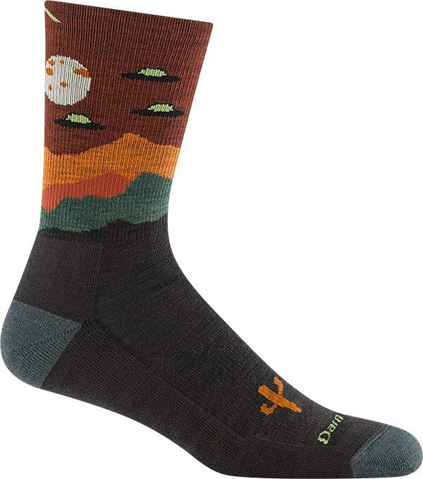 A crew sock featuring a dark gray foot and heel with a desert landscape design on the upper calf that includes a pale moon, green UFOs, and layered orange and teal mountain silhouettes against a dark brown sky.