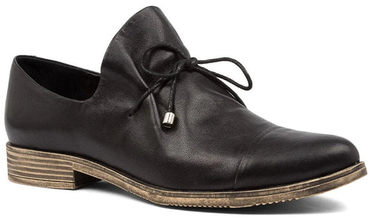 A dark colored flat dress shoe with tie closure.
