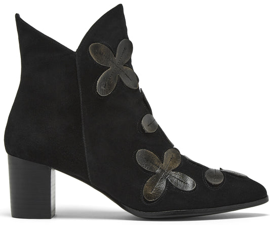 A black suede ankle boot with a block heel, featuring a pointed toe and decorative dark grey leather floral appliqués along the front seam.