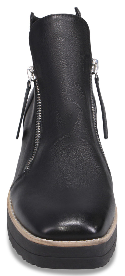 A black ankle boot with a chunky, stacked sole, featuring a square toe and silver dual side zippers with pull tabs.