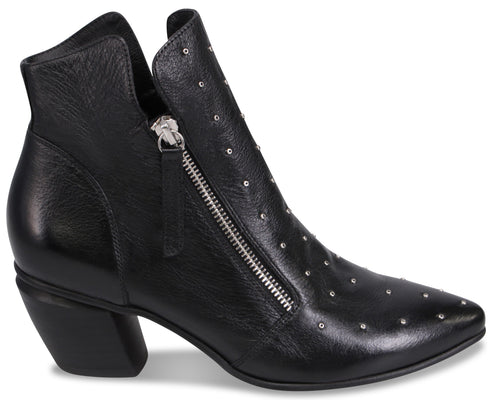 A black leather ankle boot with a pointed toe, a chunky block heel, and a side zipper closure, decorated with small metallic silver studs along the front and side.