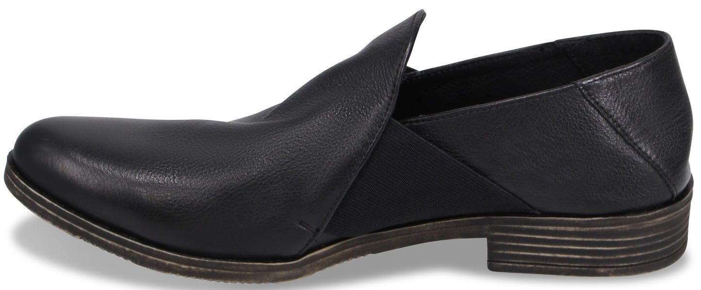 A black leather slip-on shoe with a low stacked heel and a pointed toe, featuring an elastic gore panel on the side.
