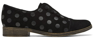A black suede oxford shoe with a repeating dark grey polka dot pattern and a small stacked wooden heel.