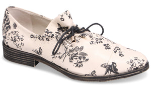 Low profile off-white dress shoe with floral pattern and black laces.