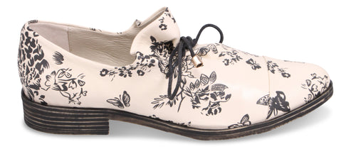 A dress shoe with a black floral pattern on a white background and a black lace.