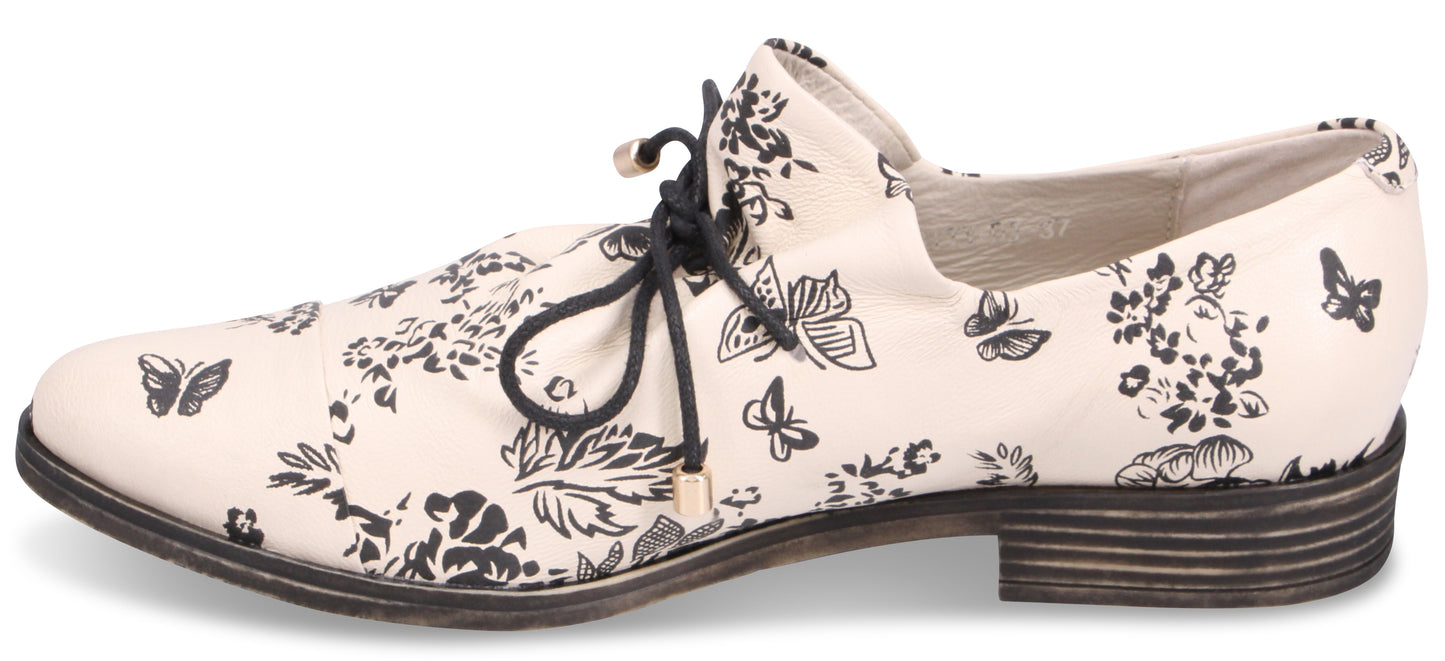 A shoe with black floral and butterfly pattern and black laces.