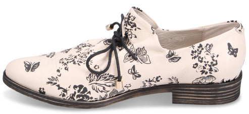 A shoe with black floral and butterfly pattern and black laces.