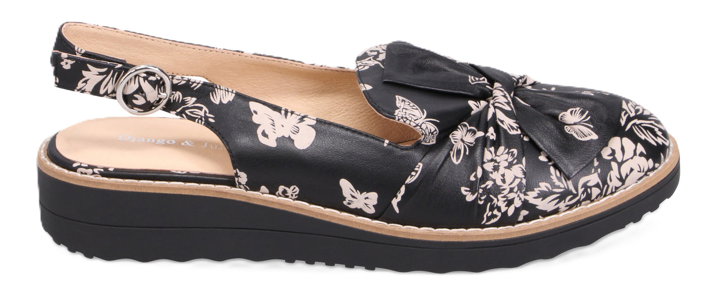 A black slingback shoe with a floral pattern and a bow.