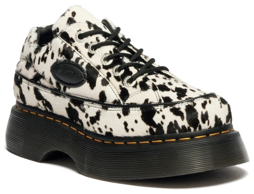 Cow print shoe with black laces and a thick black sole.